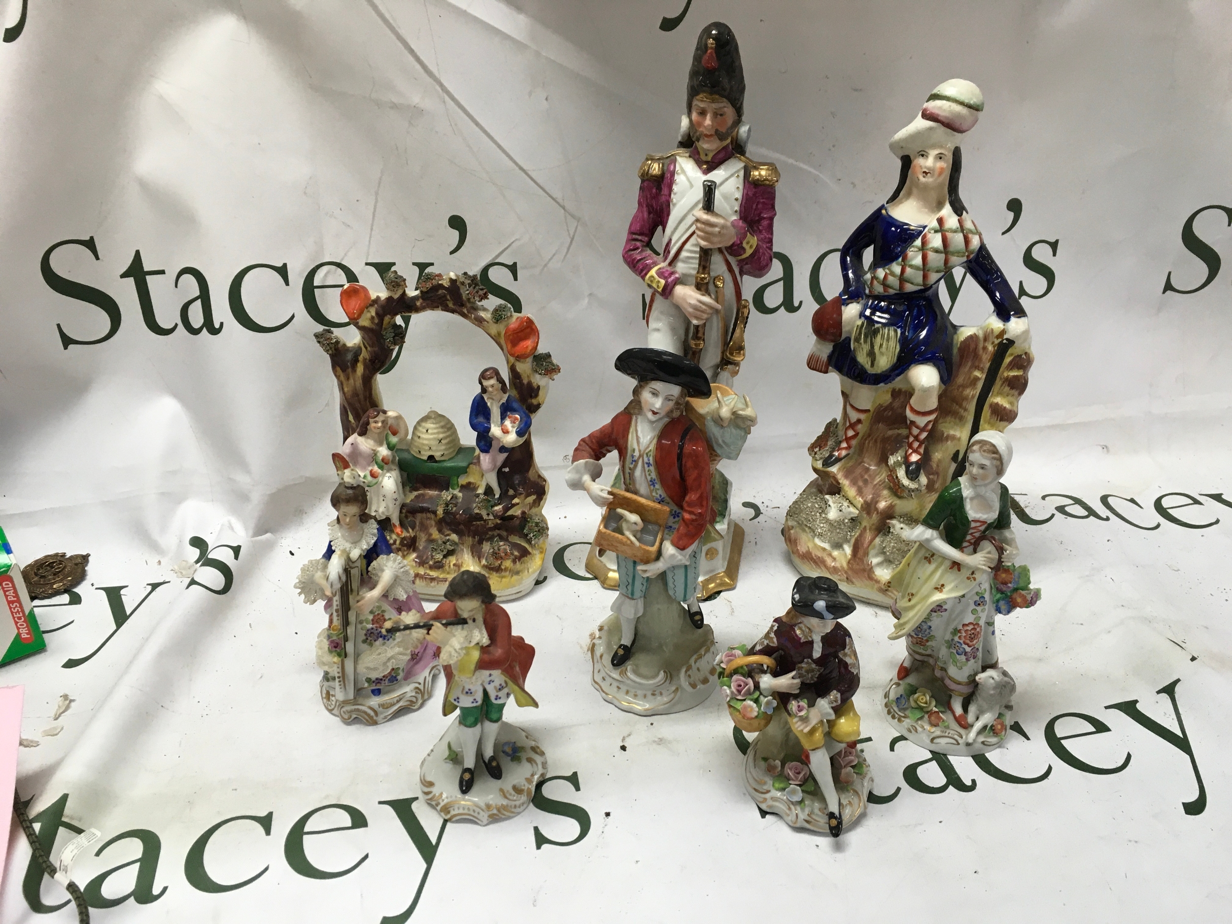 Eight 19th C figurines, to include Sitzendorf pair of musicians 13 cm, man with flower basket 12 cm, woman with tambourine and lamb 16cm, man with rabbits 19cm,  two flat-backs and a Napoleonic soldier with restoration to his neck 30cm.