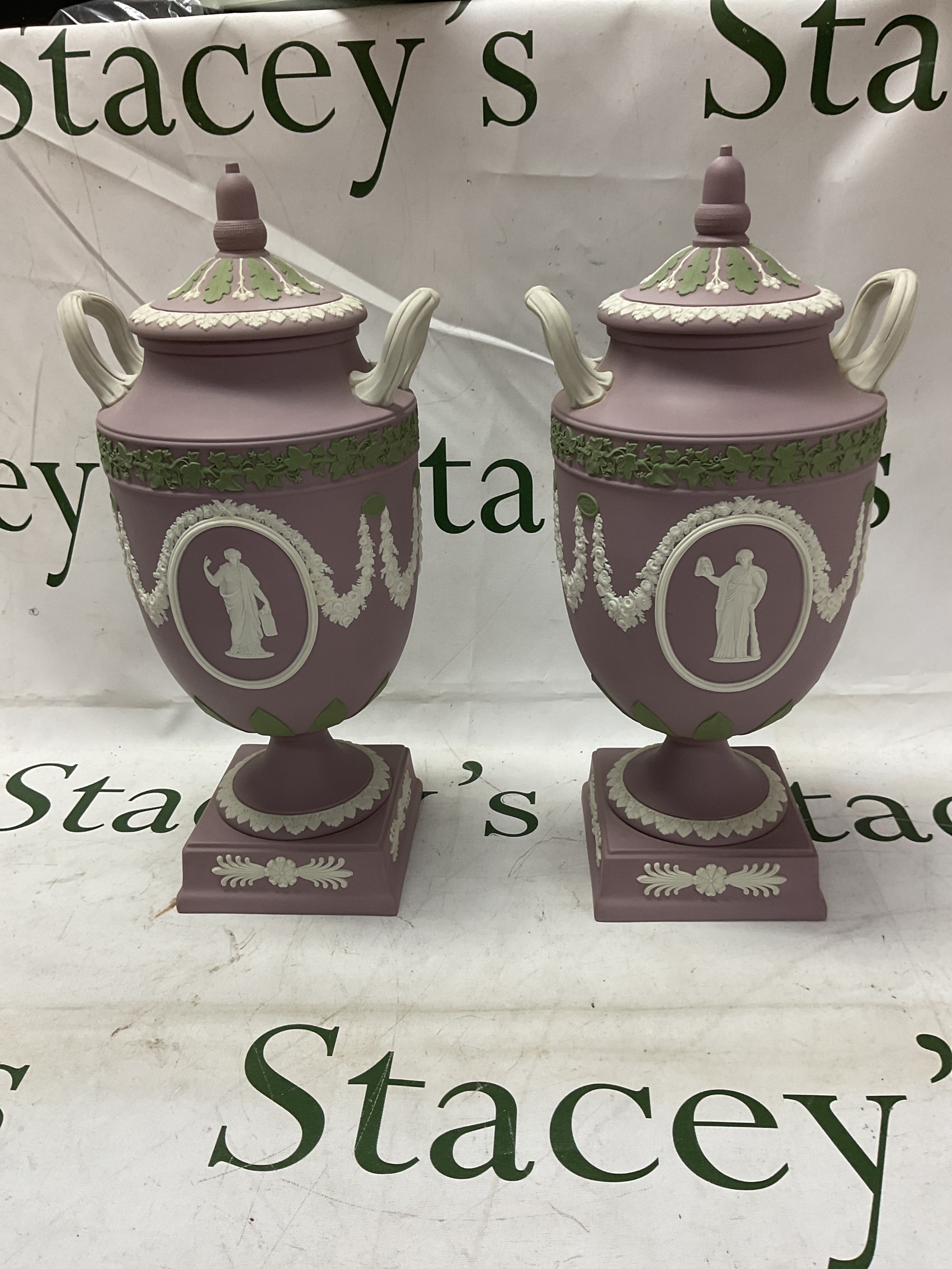 Large pair of Wedgwood tri-colour lidded vases, in lilac with green leaf detail and acorn finials to the lids, each has two oval cartouches with classical features with garlanded surround. 31cm H