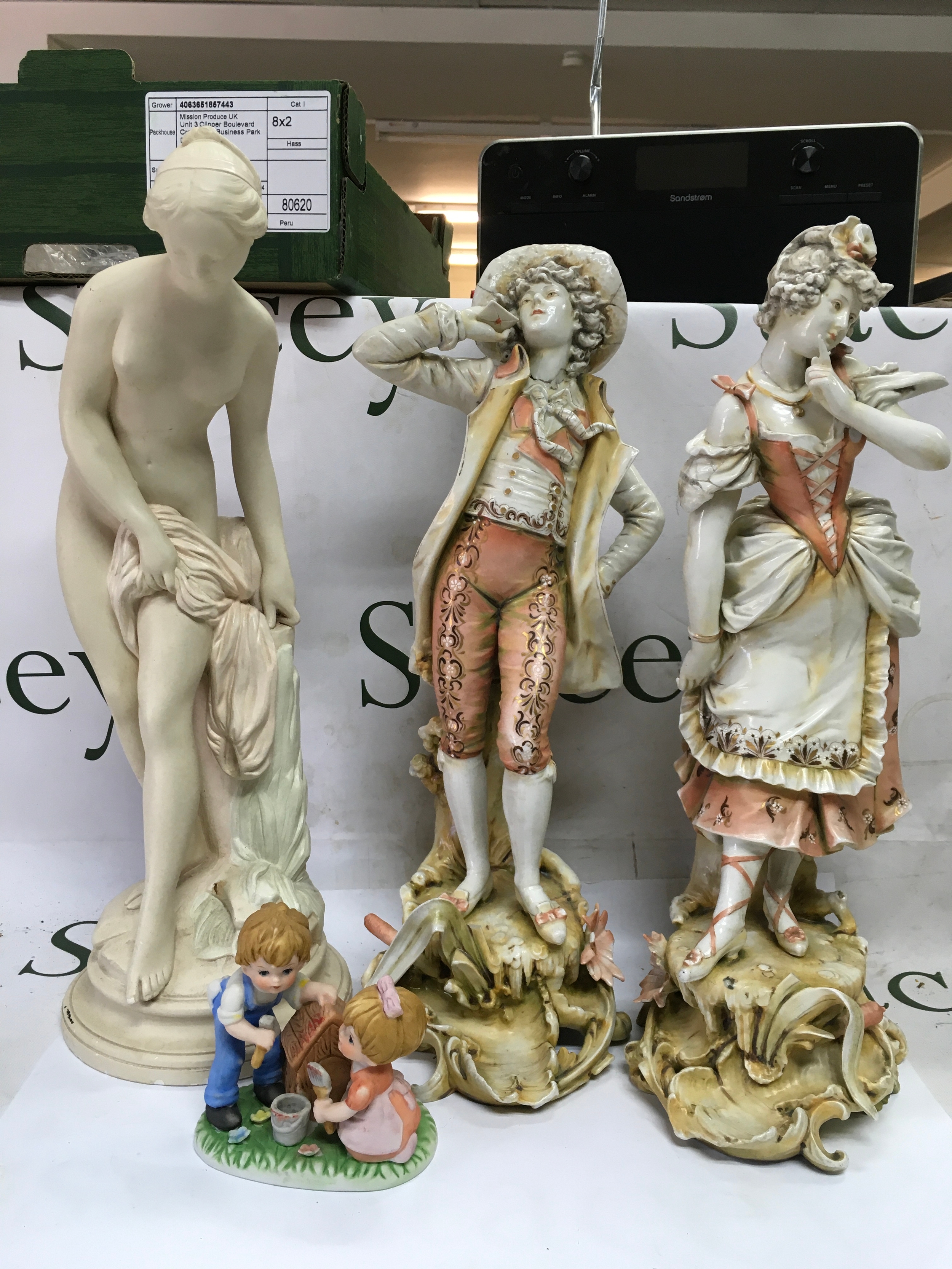 A collection of decorative figures including a 'Bathing Venus' replica, two 'Rococo Courtly' figures, and a small children figurine. 