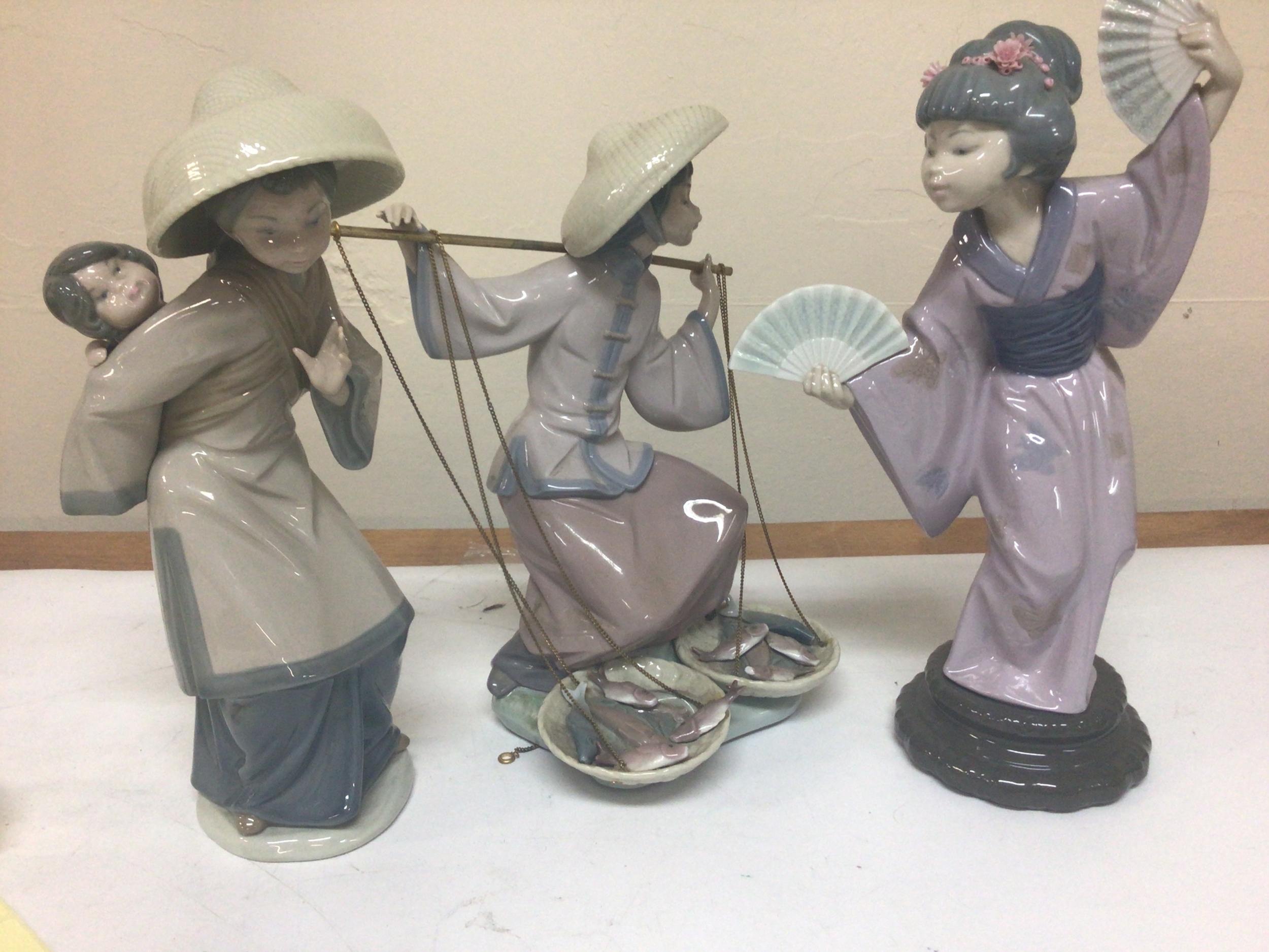   Three Lladro porcelain figures Chinese and Japanese representations in traditional dress the fish seller and two others maximum hight 30cm no obvious damage. (3) 