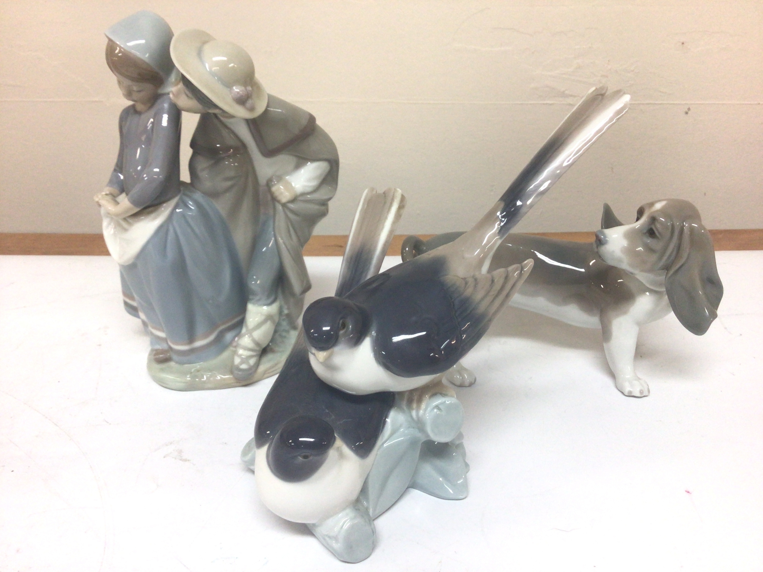   Three Lladro porcelain figures a dog, a group of birds and a young courting couple maximum hight 22cm no obvious damage. (3) 
