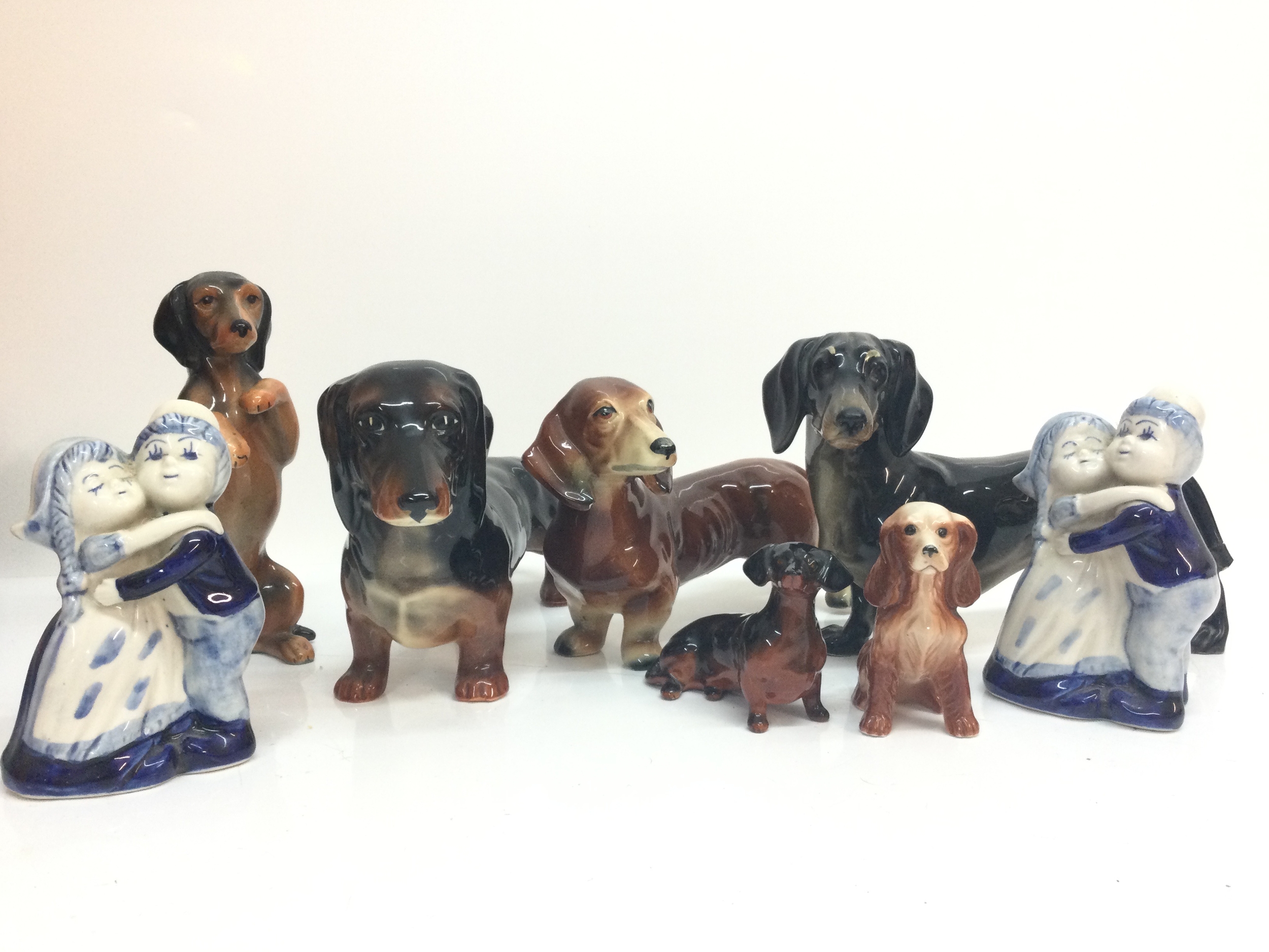 A collection of ceramic dog figures including a Beswick figure and a pair of Delft figures couple hugging 