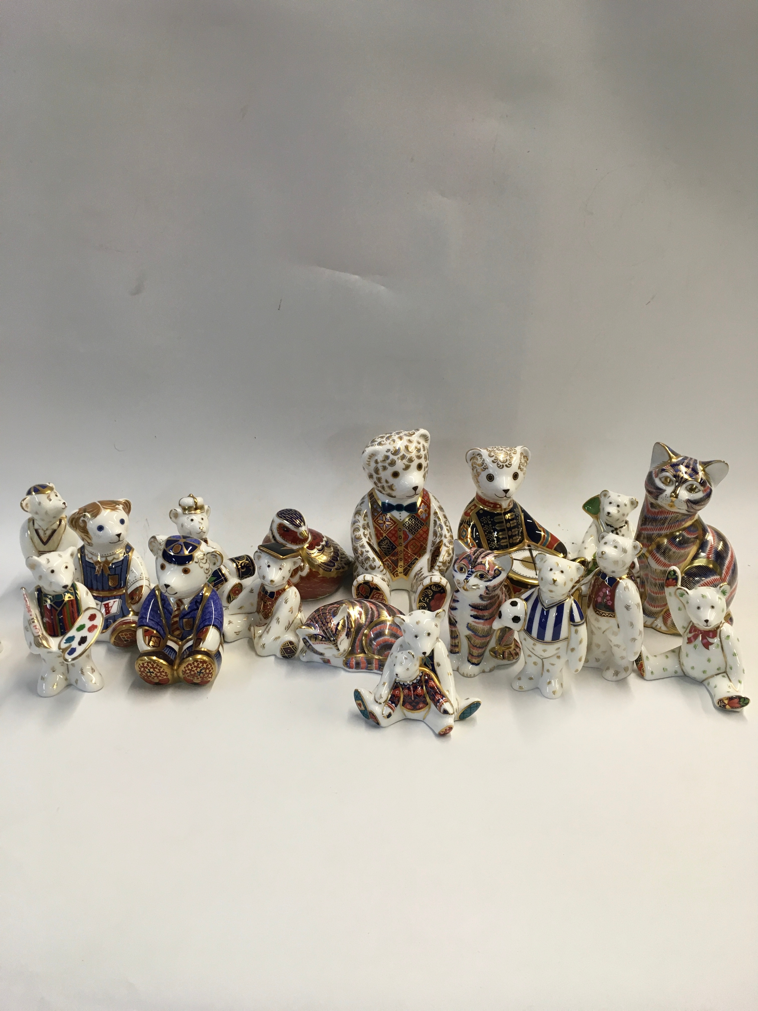 A collection of normal, gold, and silver button Royal Crown Derby figurines 