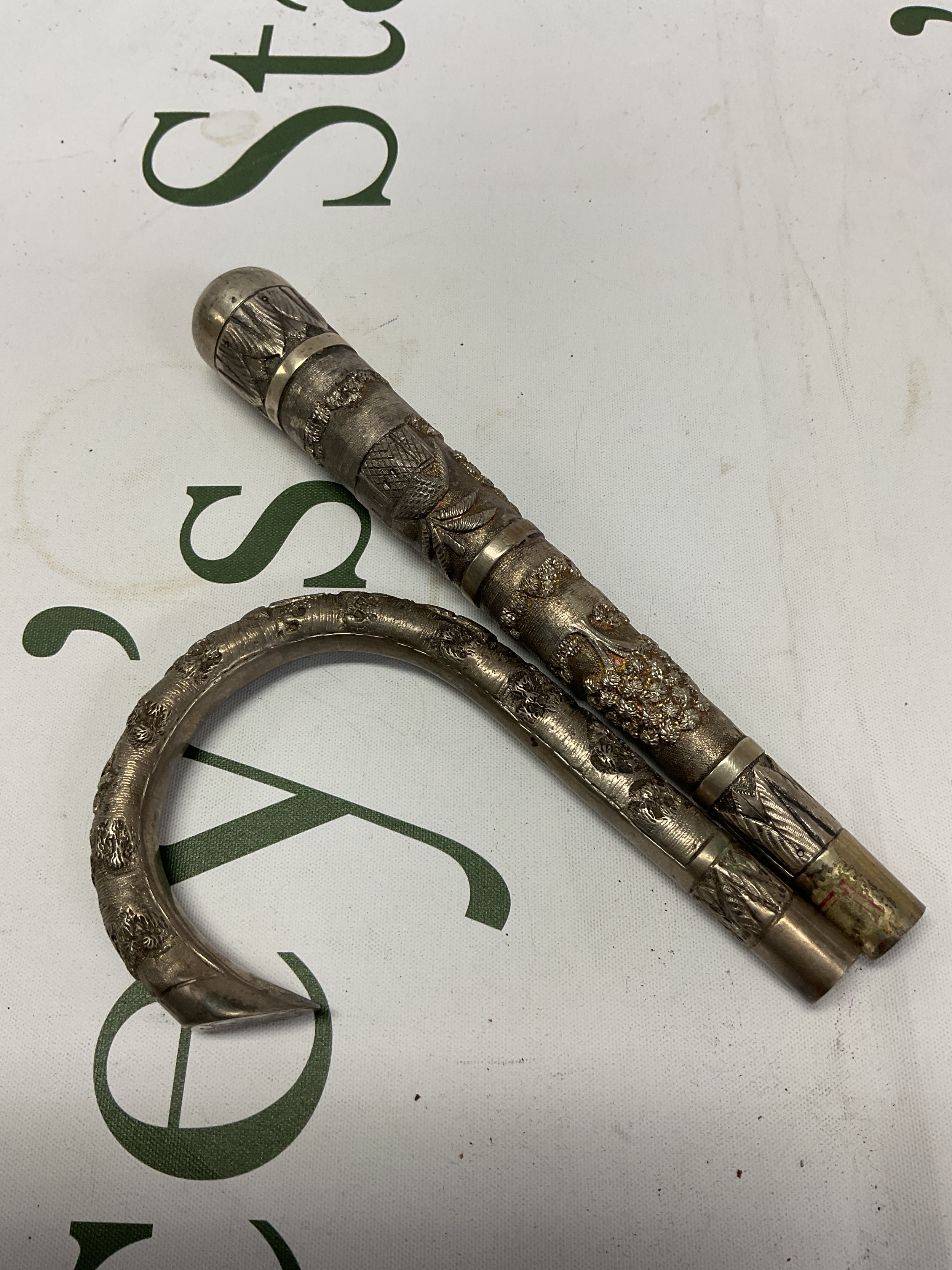 Two Indian white metal Parasol handles, with fine engraving of village scenes. Weight 150 grams.