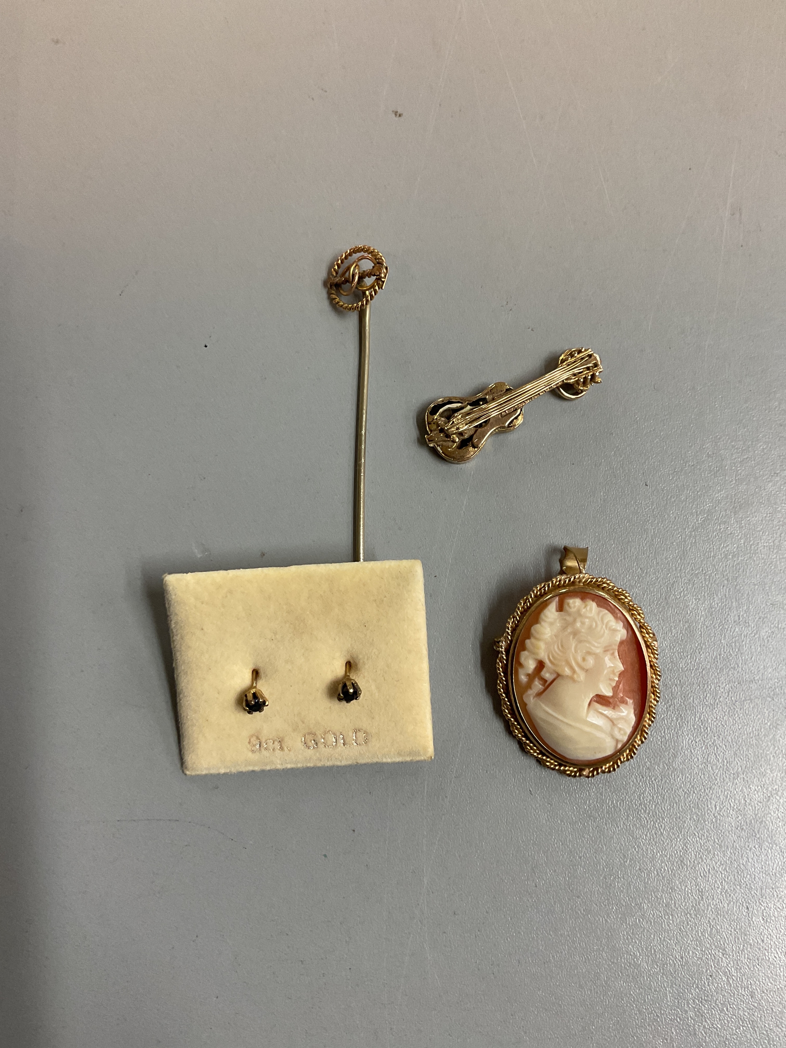 9 ct cameo, guitar charm, earrings and stick pin. Weight, 7.3 grams without stick pin.