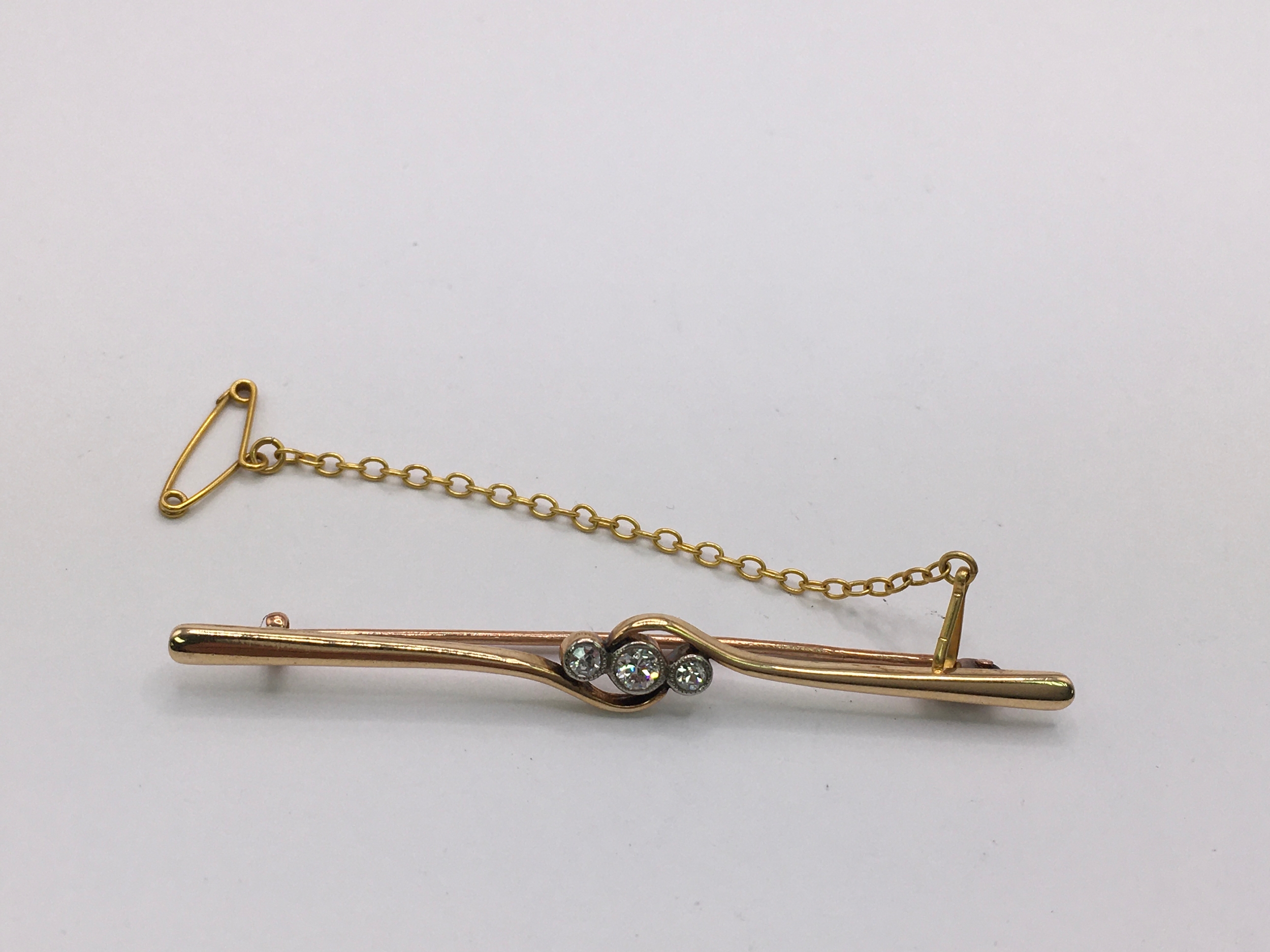 A 15ct gold bar brooch set with three diamonds. Approx L6cm