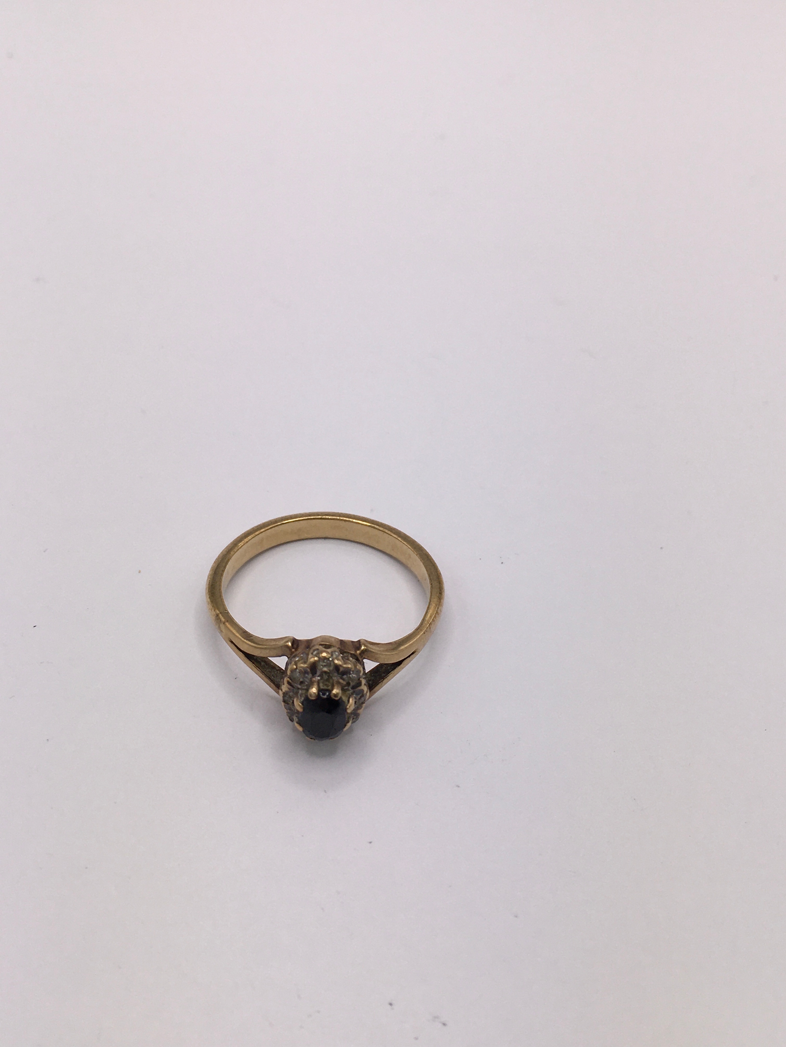 An unmarked yellow gold ring set with a sapphire in white chip surround. Size U.