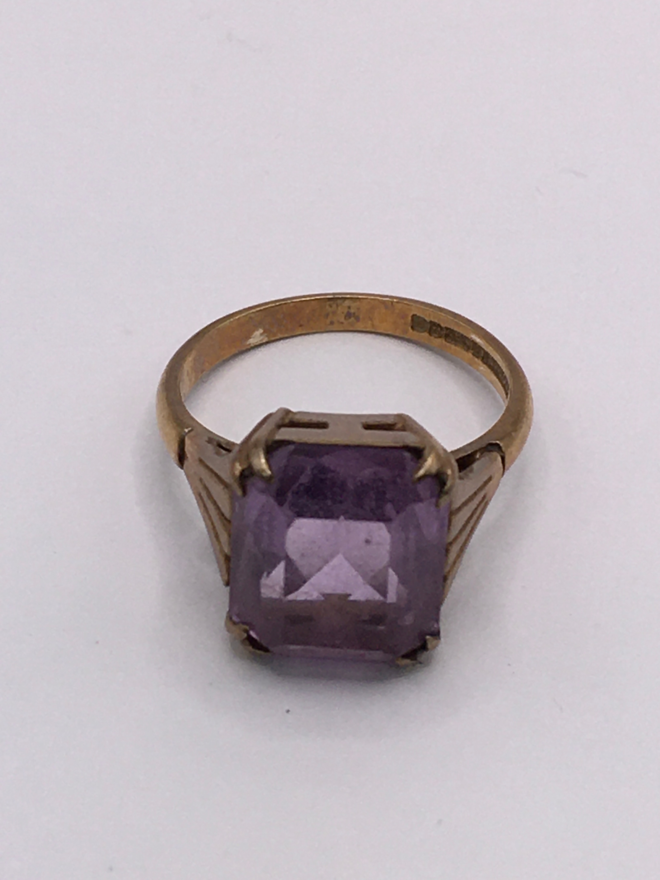 A 9ct gold ring set with an amethyst coloured square stone. Size K