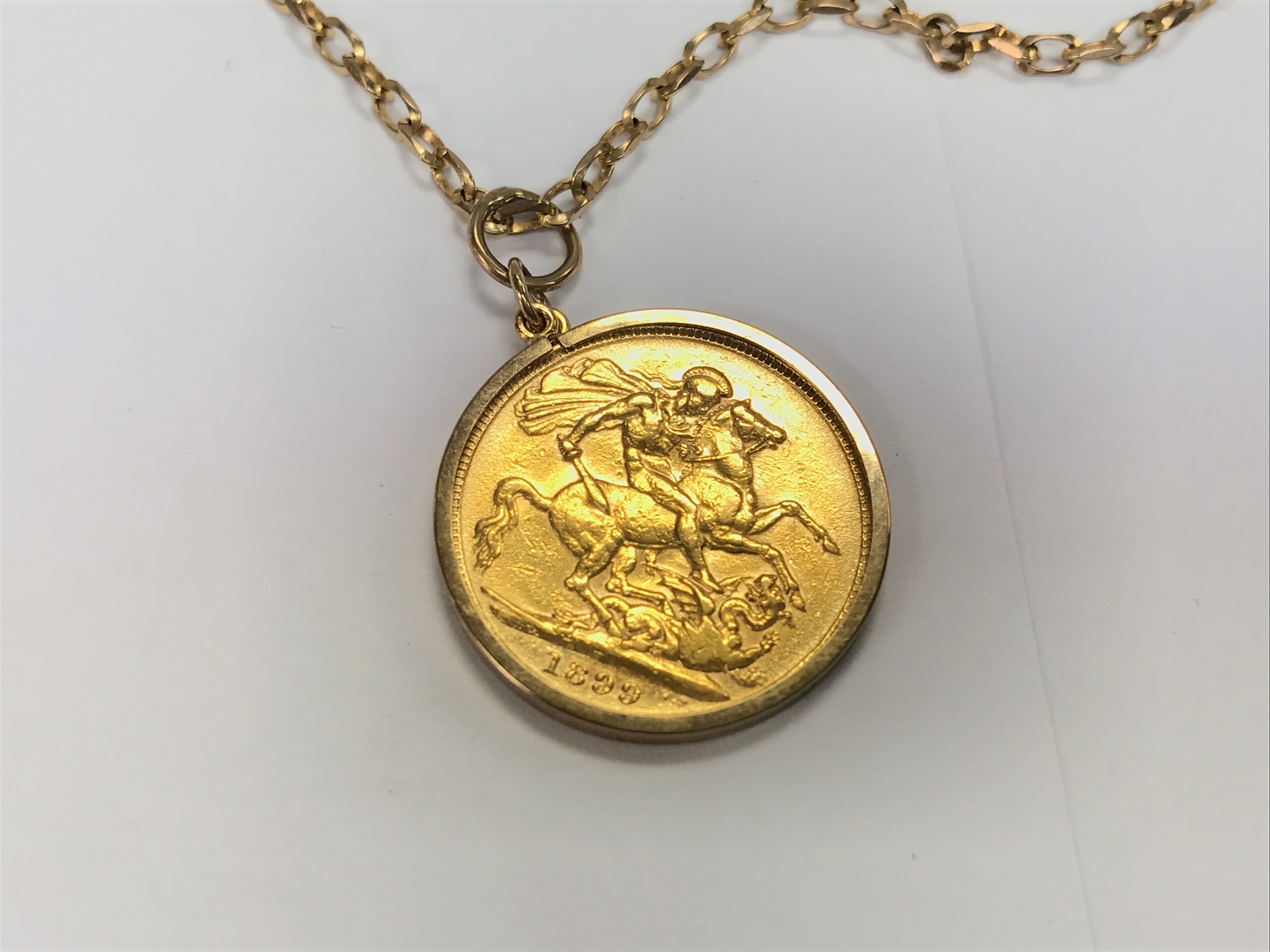 A 1899 sovereign in mount on 9ct chain. 13.5g