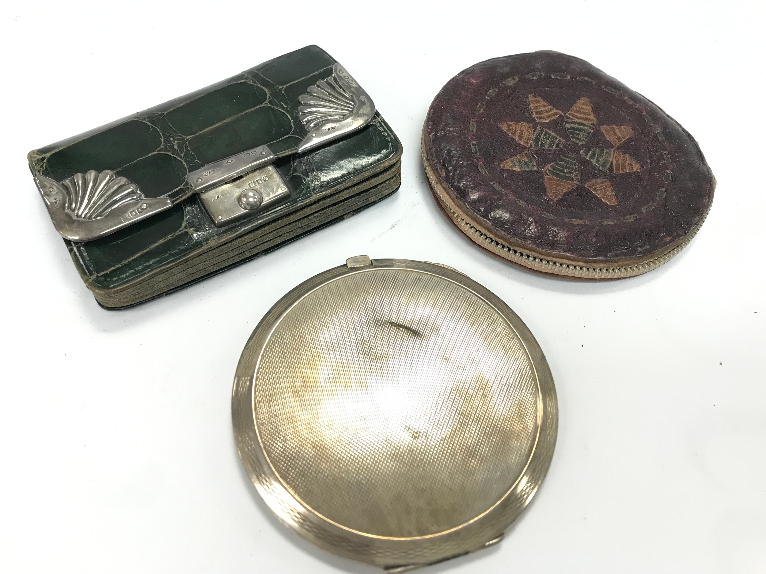 A vintage green crocodile-skin purse featuring shell-shaped silver corner mounts hallmarked London 1901 (10cm wide) and a silver hallmarked compact