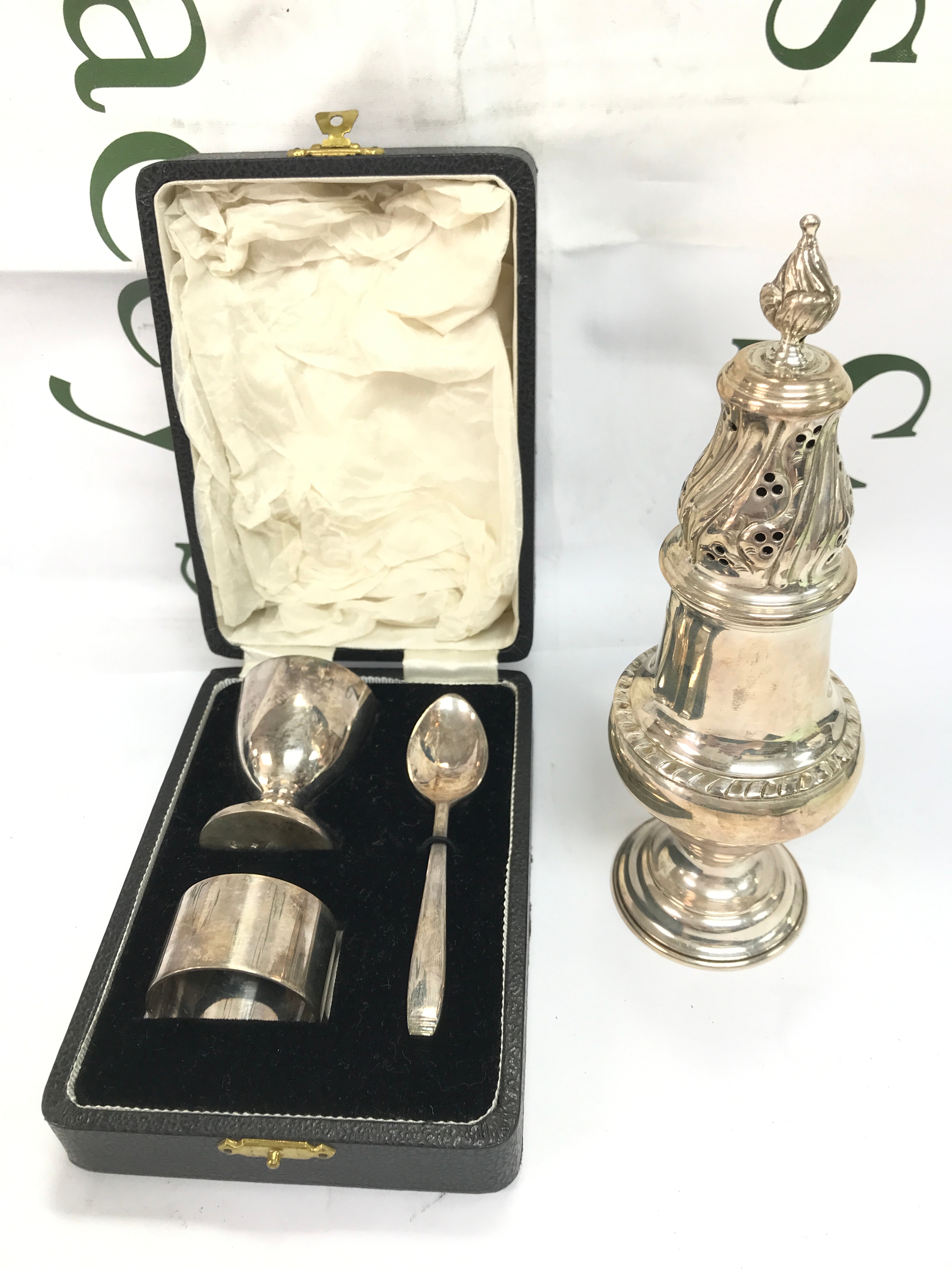 A silver hallmarked sugar shaker 153g (19cm tall) and an Elkington silver plate egg cup set boxed 