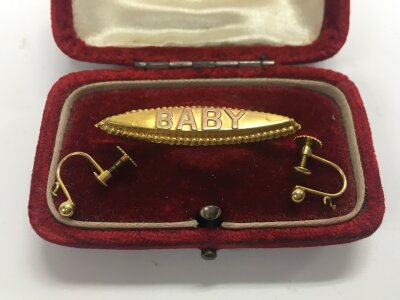 A 9ct stamped baby brooch with a set of 9ct stamped earrings. Approx weight 1.71 grams.