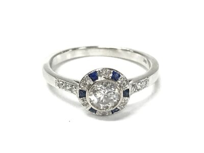 An 18ct white gold target style ring set with central diamond and square sapphires. Approximately 0.65ct diamonds and 0.10ct sapphires. Size N