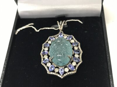 Silver pendant with floral carved aquamarine surrounded by tanzanites and diamonds on silver chain. Approximately 19.13ct Aquamarine.