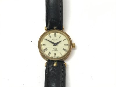 A ladies Gucci watch with 21mm dial and black leather strap.