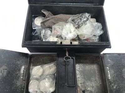 A metal cash box containing a large quantity of coins