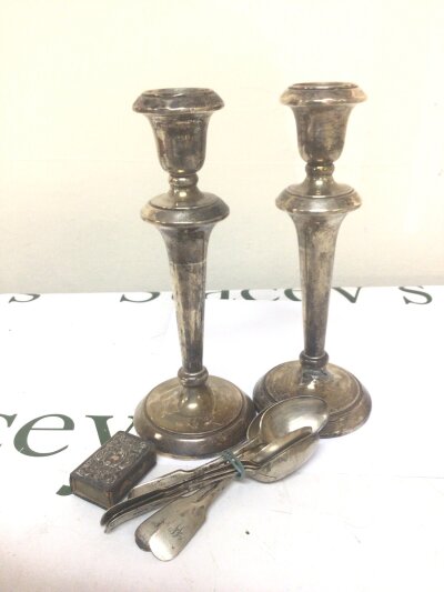 A pair of silver candle sticks loaded bases a set of silver tea spoons and a silver vesta case holder
