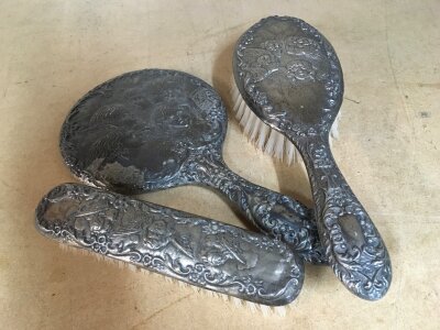 A three piece silver dressing table set, including two brushes and a hand mirror