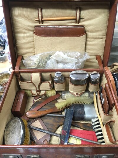 A leather case containing various silver topped tidy jars and other oddments.