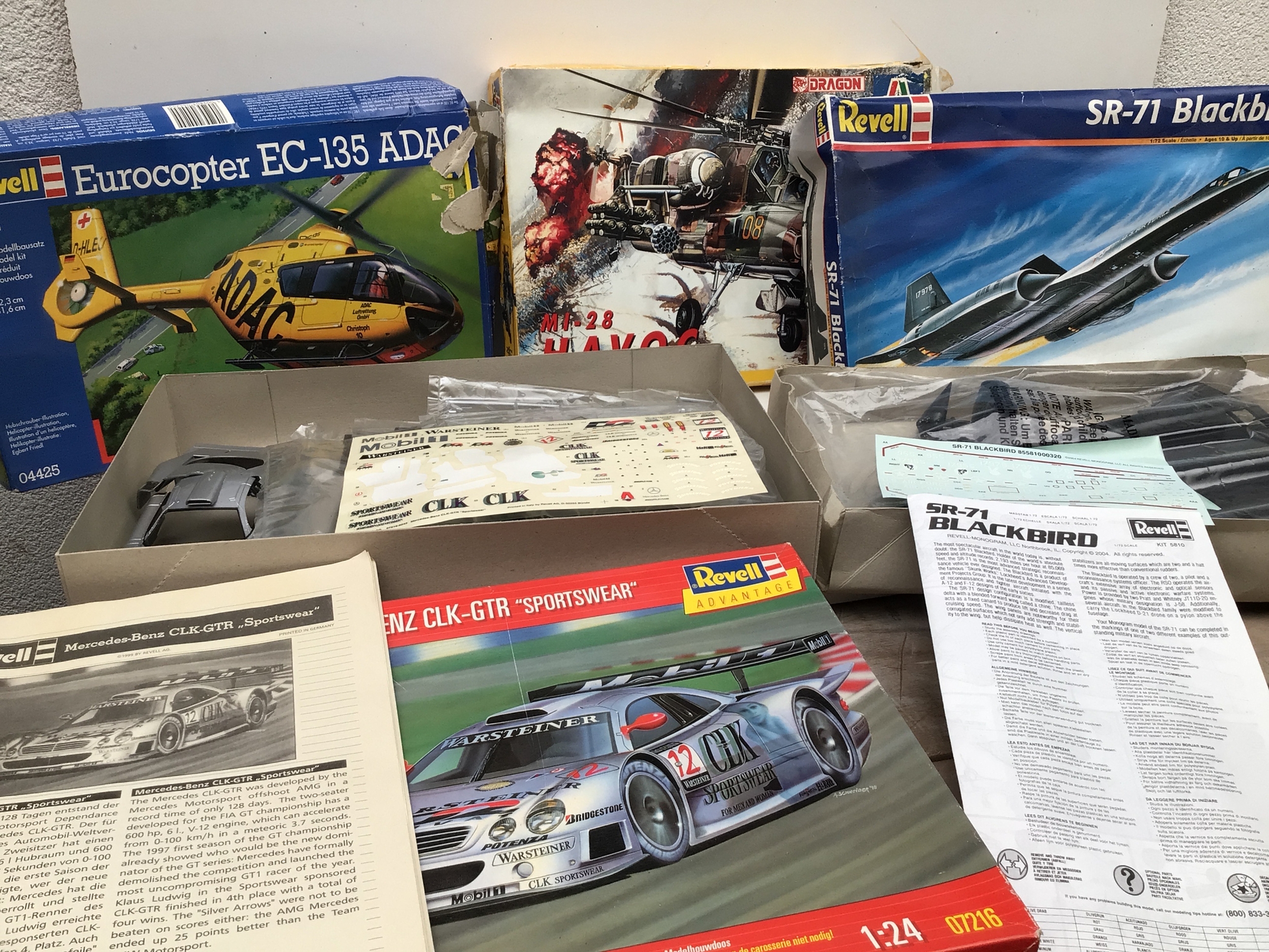 A bag containing an assorted collection of model kits in varying scales, by various manufacturers including Revell, Italeri, Monogram etc. collection features Aircraft and cars. All appear unstarted but with worn boxes.  No reserve