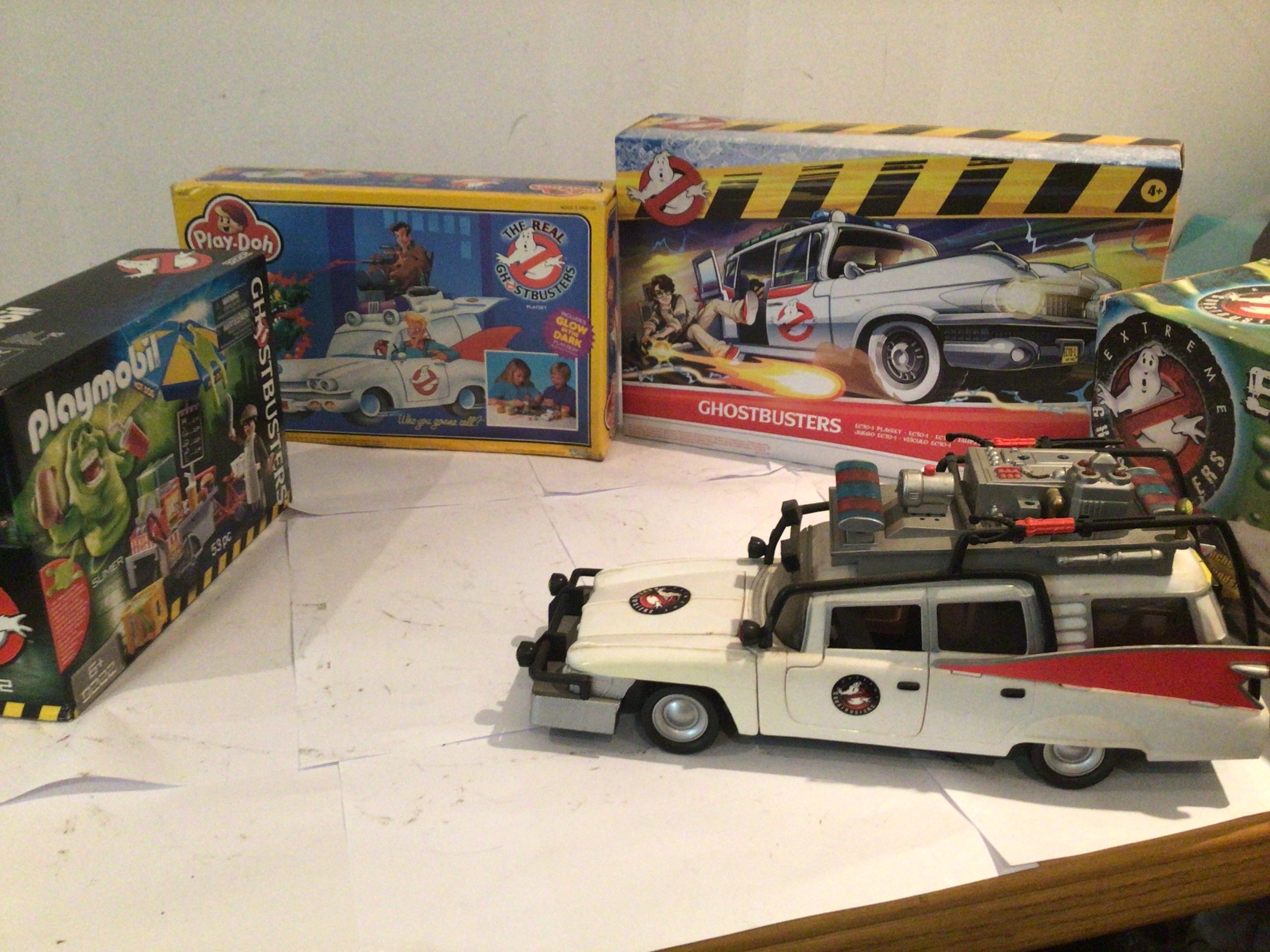 A collection of four boxed Ghostbusters toys, featuring unopened Playmobil set 9222, Play-doh set 21330 and  Hasbro ECTO-1 playset.  Also included is a ECTO-1 Exreme Vehicle in its original box.  No reserve