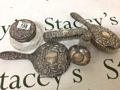 A Silver dressing table set comprising a mirror tidy jar brushes and a small dish and scent bottle.