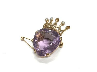 A 9ct gold brooch set with a large purple stone, some pearls missing. Approx weight 8.88 grams.