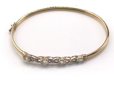 A 9ct gold bangle set with small diamonds and blue gemstones.
Approx 6.5cm and 4.08g