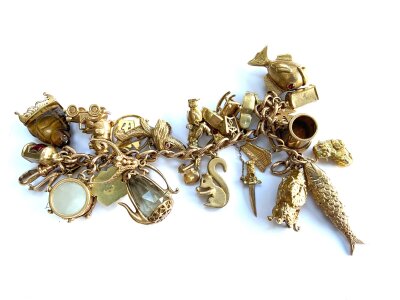 A gold charm bracelet set with a mixed collection of gold charms, approx 124g.