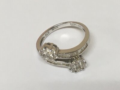 A modern design white gold 18carat ring with cross over set with a row of baguette diamonds with a pattern of brilliant cut diamonds. Size M-N