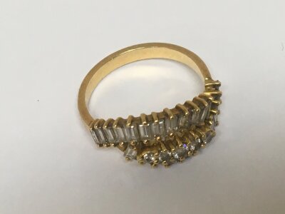 An unmarked gold ring set with a pattern of baguette diamonds and brilliant cut diamonds with three shaped rows ring size O-P weight 4g