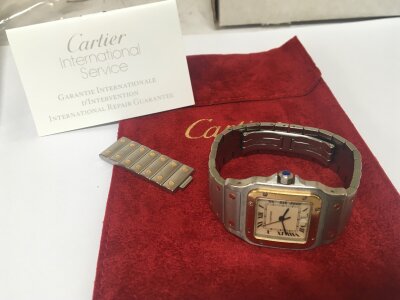 A Cartier Santos Galbee steel and gold Midi watch with blue sapphire winding crown the watch with date aperture serial number 18790125839. The watch serviced by Cartier 22/March/2026.  With extra links and Cartier service papers and watch pouch.
Case is 29mm. Watch is running.
