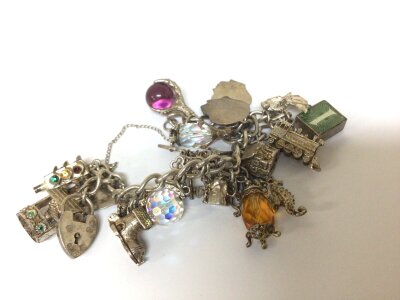A Silver charm bracelet with numerous charms attached with some coloured stones. Weight 77g