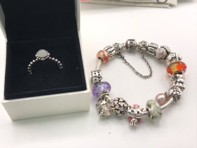A Pandora charm bracelet with a number of charms and a Pandora ring size M 1/2 both with boxes.