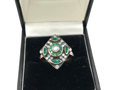 An unmarked rose gold and silver topped ring set with RBC diamonds and marquise and calibre cut emeralds.