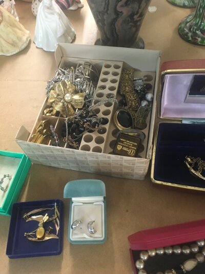 A box containing costume jewellery various including brooches necklaces and earrings.