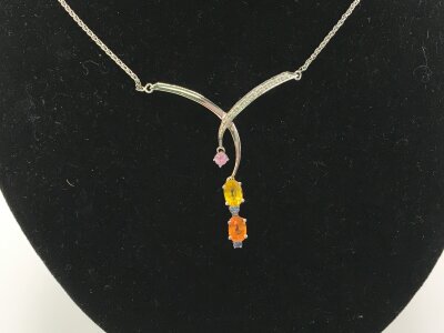 An 18ct white gold necklace and pendant set with coloured stones.
5.11g