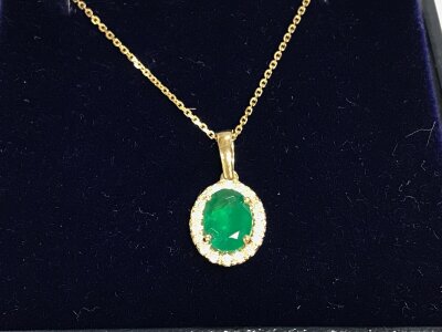 A 9ct gold oval emerald and diamond cluster pendant on a 9ct gold chain. Emerald 1.03ct and diamonds 0.13ct approximately.
