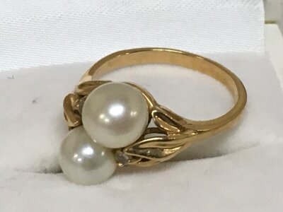 An unmarked yellow gold ring with two central pearls, flanked by diamond chips