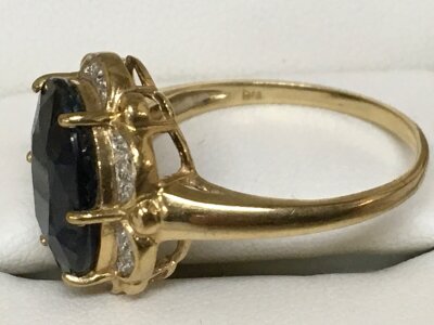 An unmarked yellow gold ring inset with a dark gemstone flanked by diamond chips