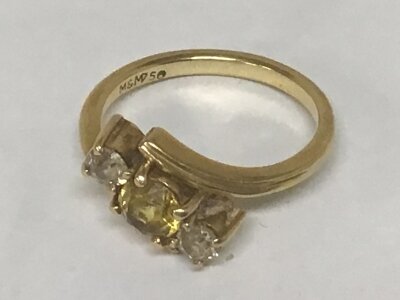 An 18carat gold ring set with a central yellow stone flanked by two white stones weight 5g