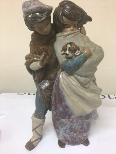 A large Lladro figure group facing the wind a young boy and girl cradling a puppy designed  by Juan Huerta Height 37cm no obvious damage
