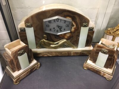 An art deco marble clock featuring geometric contours and a brass female figure. With garniture and key. Clock 30cm tall 46cm wide