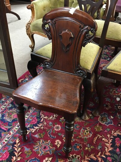 An Early Victorian mahogany hall chair with a solid shaped back and seat on turned legs.