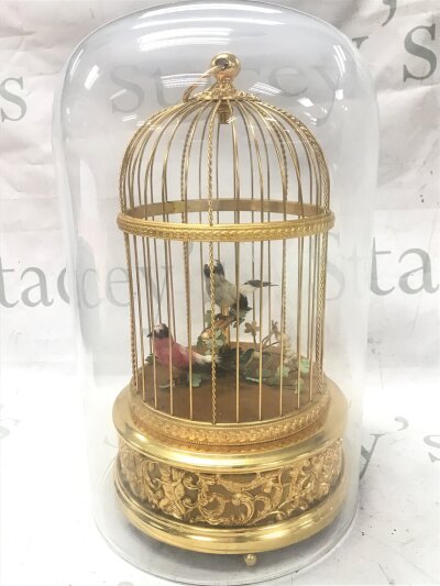 An ornate Reuge Music Swiss gilt singing birds in a cage automaton, with a glass dome. 28cm tall, 16cm wide. Seen working