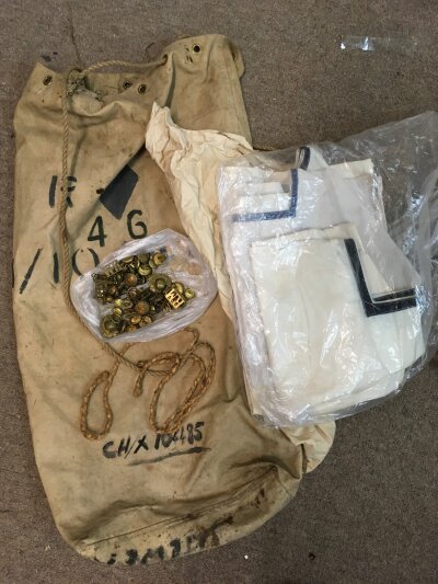 Naval uniforms in a kit bag with buttons