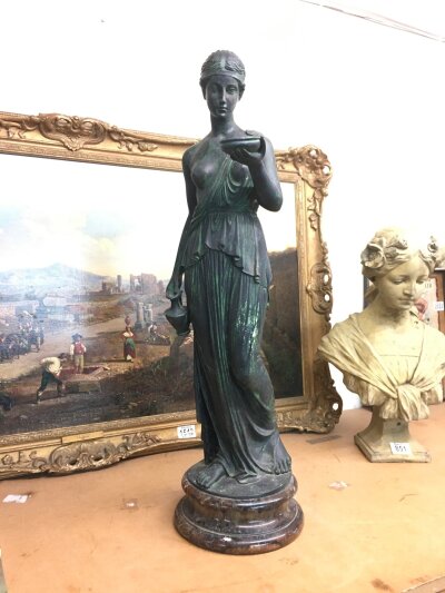 A classical figure, The Greek goddess Hebe, depicted as the cupbearer to the gods holding a bowl and a ewer, resting on a polished marble base. 66cm tall