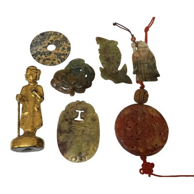 A small collection of orientalist items to include a small carved standing deity, and a selection of jade and hardstone carved amulets.
