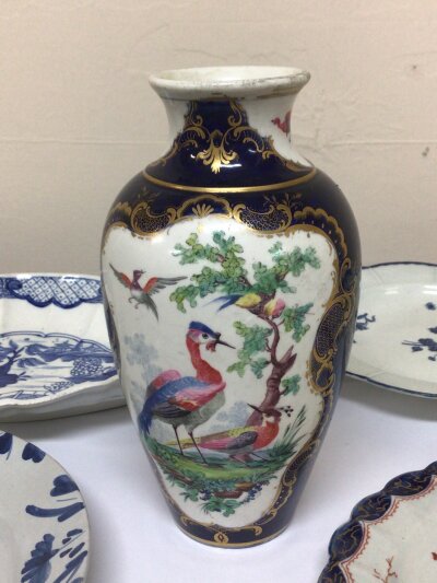 A collection of 18th century English porcelain including a Worcester vase decorated with exotic birds on a white ground and deep blue glaze with applied gilt cross hatch marks in underglaze blue Hight 20cm and five dishes 18th century delft  a Caughley plate and others (6)