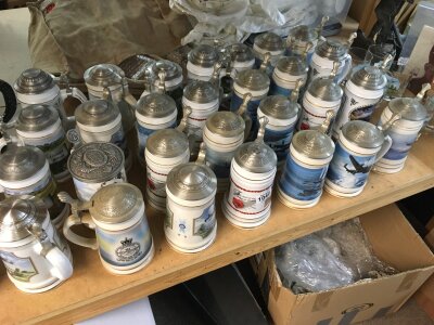 A mixed assortment of ceramic tankards and six aeroplane glasses.